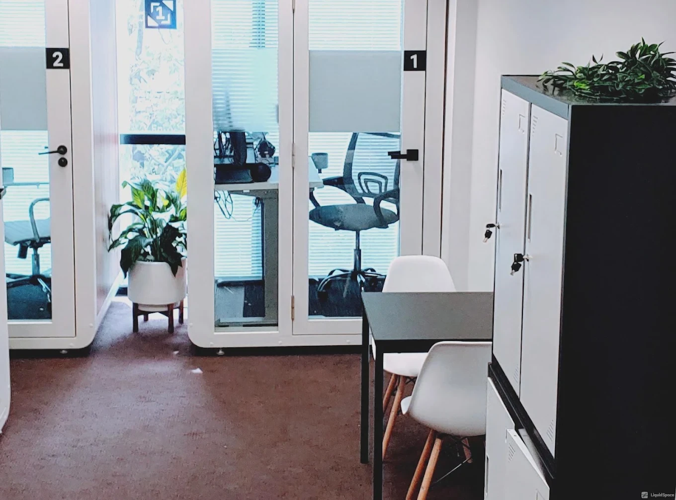 Inside 1Smart.Space Docklands: two numbered white interview pods with glass doors, desks and office chairs, next to a bank of lockers